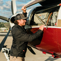 A man in the Flight Outfitters Airfoil Jacket standing beside an aircraft.