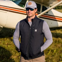 Man wearing Flight Outfitters Insulated Airfoil Vest in front of high-wing aircraft