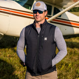 Man wearing Flight Outfitters Insulated Airfoil Vest in front of high-wing aircraft