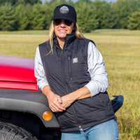 Woman wearing Flight Outfitters Insulated Airfoil Vest in front of red Jeep