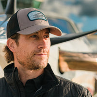 A man wearing the Flight Outfitters Chart Topo Hat, displaying the detailed front graphic in an adventure-ready setting.