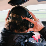 A man wearing the Flight Outfitters Chart Topo Hat with an aviation headset, emphasizing the back for comfort.