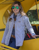 Another view of a woman wearing the Women's Fairbanks Fleece in Heather Stone in front of an aircraft, emphasizing its professional style.