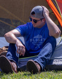 A man sitting in front of a tent wearing the Flight Outfitters Mountain Range T-Shirt, emphasizing its adventure-ready style.