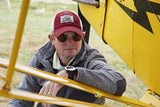 A man wearing the Flight Outfitters Seaplane Hat while sitting in front of an aircraft, emphasizing its aviation-inspired appeal.