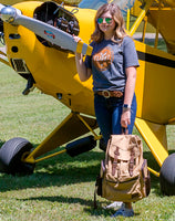 A woman holding the Flight Outfitters Bush Pilot Rucksack, highlighting its portability and style.