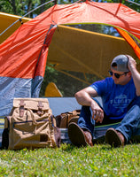 A man with the Flight Outfitters Bush Pilot Rucksack in front of a tent, showcasing its suitability for outdoor adventures.