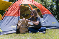 A woman opening the Flight Outfitters Bush Pilot Rucksack, showing easy access to its compartments.